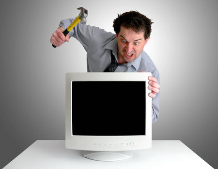 Tired, freaked-out business man preparing to smash a computer monitor with a hammer.