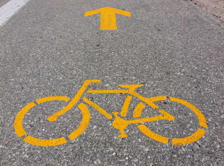 Bycicle and arrow symbols painted in yellow on highway shoulder.の写真素材