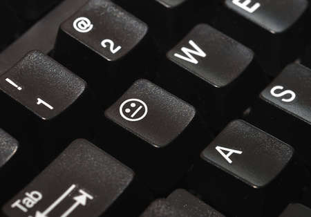 Close-up of a computer keyboard, with a non-emotional face on one of the keys.の写真素材