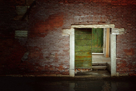 Old, weathered doorway in a brick wall along a canal in Venice, Italy. Image has a light pastel on canvas effect applied to it.の写真素材