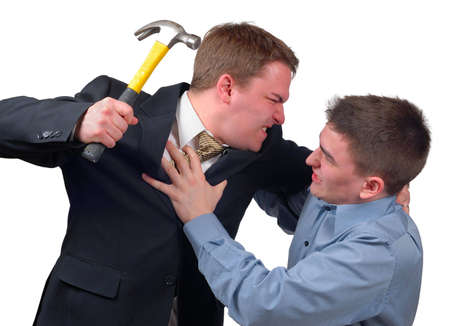 Angry young man in a business suit attacking a frightened young man in a dress shirt with a hammer.の写真素材