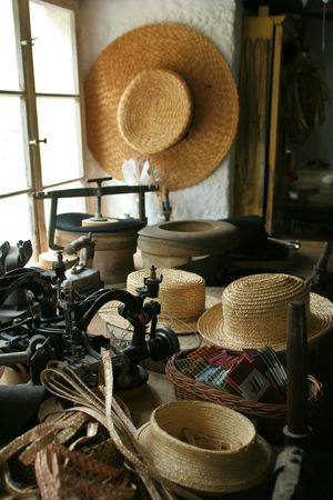 Old-fashioned hat-making shop with straw hats and an old-time sewing machine.の写真素材