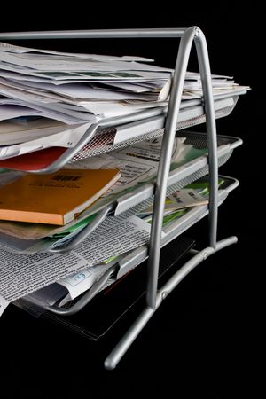 In-basket overflowing with papers,mail and other documents. Isolated on black background.の写真素材