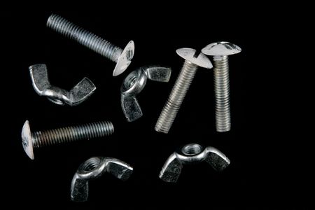 a group of wing nuts and bolts, isolated on a black background.の写真素材