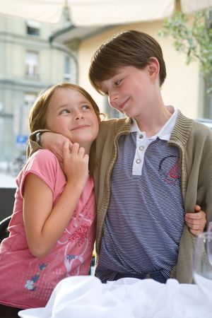 A boy and girl, brother and sister, share a hug and a tender smile.  Outside, summer urban setting.  Portrait, light tones.の写真素材