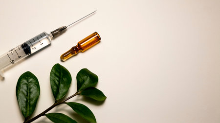 Syringe and ampoule on a light background with green leaves.