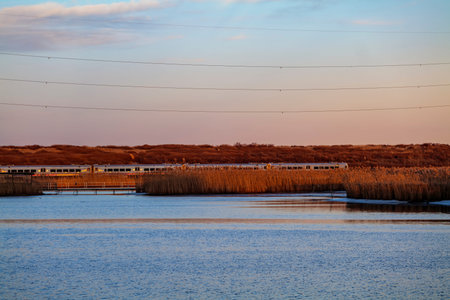 Railroad Tracks Against Sky During Sunset with blue sky, electric pylons line runs parallel to the...