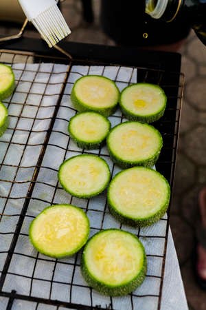 Hand prepares raw sliced vegetables - zucchini, squash, eggplant roasting on the grill. High quality photoの写真素材