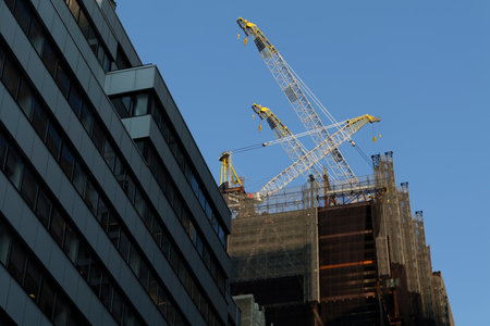 High-rise construction tower crane against the backdrop of a beautiful blue sky. City construction. High-quality photoの写真素材