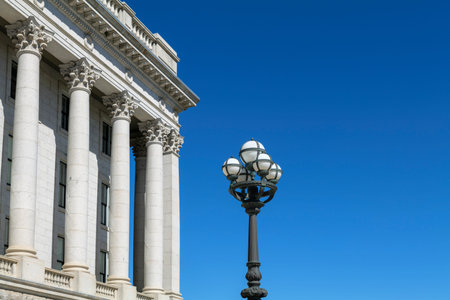 Part of the Capitol building with columns and street lamp on blue sky background with copy space....