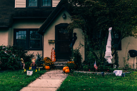 Many bright and colorful inflatable Halloween decorations, skeletons, carved pumpkins, and scarecrows in the driveway and front lawns of a residential house. High-quality photoの写真素材
