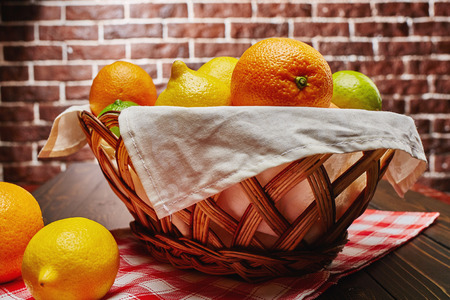 Basket with citrus fruit. Vitamin. Health. Freshness. Wood table. Brick background.の写真素材