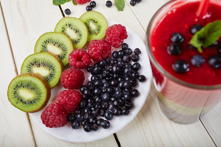 Berry smoothie.Fresh summer cocktail.Blueberry,raspberry,kiwi.Vitamin A. Vitamin C.Checkered napkin.On white wooden table with ingredients.Healthy lifestyle.Diet and weight loss concept.Top viewの写真素材
