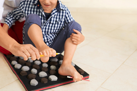 Little boy on massage mat doing exercises for flatfoot prevention.Child flatfoot treatment using special massage carpet.Foot strengthening exercises.Podiatry clinic. の写真素材