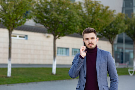 Portrait of handsome serious man in casual wear holding smartphone. Successful manager makes a call....