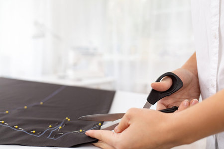 Young female dressmaker cuts dress detail on the sketch lines with scissors .Close-up view fashion...