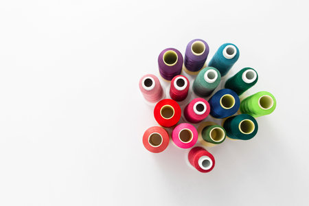 Row of multicolored spools of sewing thread on a white background. Workplace of seamstress. Sewing...