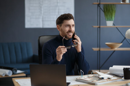 Architect talking on the phone in office. Confident businessman negotiates with business partners....