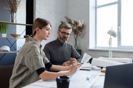 Engineer team working in office with blueprints and architect equipment, sketching, negotiating and planning construction project. Partners discussing at work. Business construction concept.の写真素材