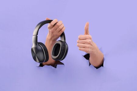 Bluetooth headphones stick out from a Blue torn background. Copy Space. I love music. Like music.の写真素材