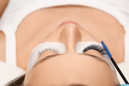 Eyelashes extensions. Fake eyelashes. Eyelash extension procedure.Close up portrait of woman eye...