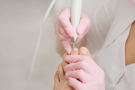 Patient on medical pedicure procedure, visiting podiatrist.Professional hardware pedicure using electric machine.Peeling feet with special electric device.Foot treatment in SPA salon.Podiatry clinic.の写真素材
