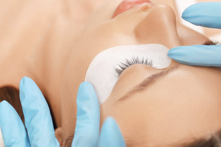 Eyelashes extensions. Fake eyelashes. Eyelash extension procedure.Close up portrait of woman eye...