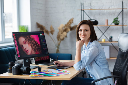 Portrait of graphic designer working in office with laptop,monitor,graphic drawing tablet and color...