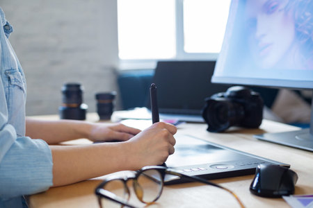 Close up portrait of graphic designer hands retouching images using graphic drawing tablet in...