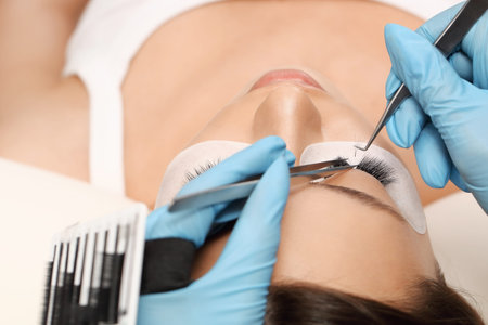 Eyelashes extensions. Fake eyelashes. Eyelash extension procedure.Close up portrait of woman eye...
