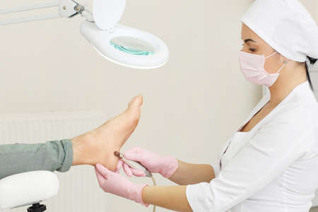 Peeling feet with special electric device.Professional hardware pedicure using electric machine.Patient on medical pedicure procedure, visiting podiatrist.Foot treatment in SPA salon.Podiatry clinic.の写真素材