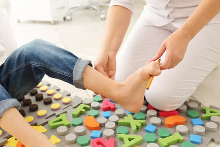 Child flatfoot treatment using special massage carpet.Little girl on massage mat doing exercises for flatfoot prevention.Foot strengthening exercises.Podiatry clinic.の写真素材