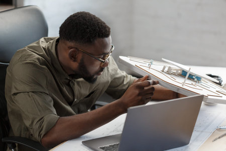 Afro-American architect works in office with 3d model. Business portrait of black handsome bearded...