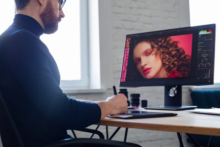 Retouching images in special program.Portrait of graphic designer working in office with...