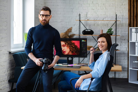 Photographer and graphic designer working in office with laptop, monitor, graphic drawing tablet and...