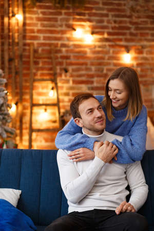 Portrait of beautiful smiling couple hugging at Christmas eve. Beautiful young couple at home enjoying spending time together. Winter holidays, Christmas celebrations, New Year concept.の写真素材