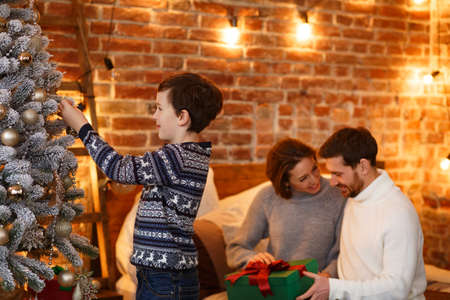 Little boy at home decorating a Christmas tree. Spending time together, relationships and people concept. Winter holidays, Christmas celebrations, New Year concept.の写真素材