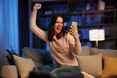 Happy young woman surprised by the good shocking and unbelievable news, making yes gesture while...