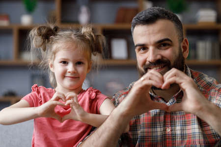 Young handsome father and little cute daughter smiling looking at camera showing symbol making with fingers heart shape sign of love. Family love and family bond concept. Fathers day.の写真素材