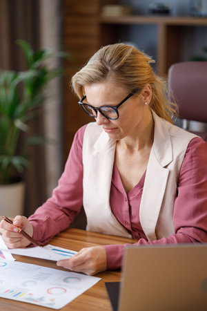Portrait of adult businesswoman wearing eyeglasses working at office. Female manager doing...