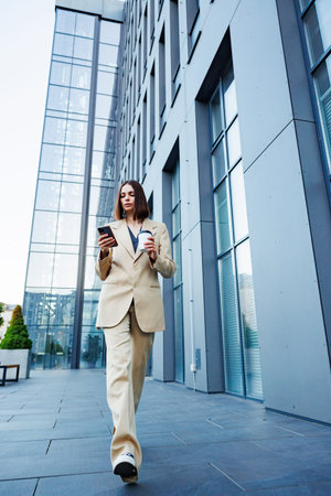 A young brunette girl against the backdrop of a business center, office center. On the go, he reads...
