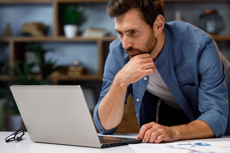 Handsome male businessman manager working behind a laptop in a stylish home office. Remote work at home. Portrait of a successful freelancer.の写真素材