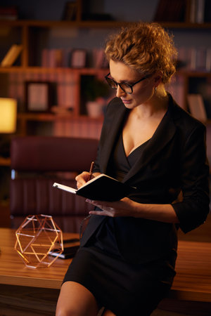 Purposeful young business woman, professional entrepreneur, reads a book. Business woman in a beautiful office in cinematic light. A beautiful portrait.の写真素材
