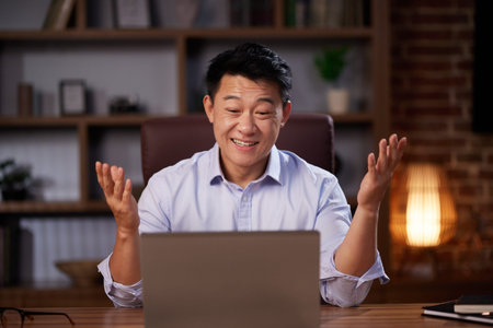 Asian man holding online webinar using laptop webcam, sitting in a home office. Man having online...
