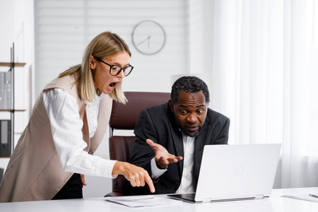 Angry female boss scolding African American office worker. A demanding manager-leader is annoyed by laziness and mistakes in the work of an employee. Authoritarian leadership, malfeasance, racismの写真素材
