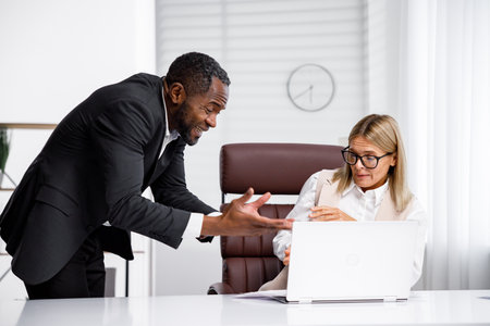 Angry African American boss scolds woman office worker. A demanding manager-manager is annoyed by laziness and mistakes in the work of an employee. Authoritarian leadership, malfeasance, racismの写真素材
