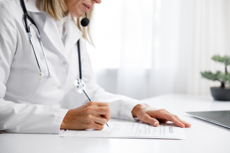 Woman medic, doctor writes out a prescription. Makes an entry in the medical record. Medical background.の写真素材