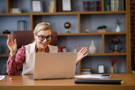 Happy businesswoman surprised by the good news while looking at laptop sitting at office.Manager enjoying success, celebrating victory,make good deal, get profit. The rise of cryptocurrencies conceptの写真素材