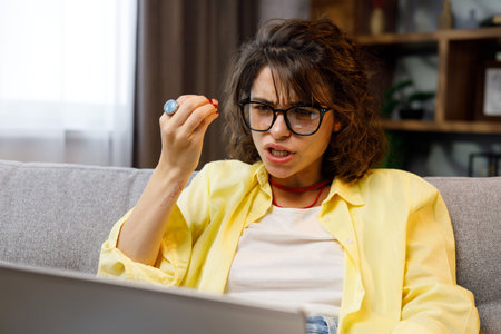 Young female freelancer, stressed out from working online. Focused girl uses laptop for nervous conversation and consultations online at home, female user, remote work on the Internet, programmingの写真素材