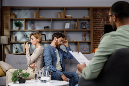 A quarrel between a husband and wife at a psychotherapists appointment. A visit to a family psychologist for a married couple. An African-American doctor consults an unhappy couple.の写真素材